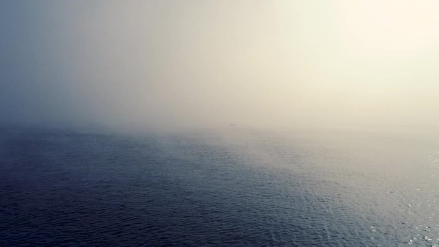 Fog and sailing fishing boat in the sea, aerial sunrise view