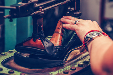 Fototapeta na wymiar Worker in the handmade footwear industry, is fixing sole for shoes.