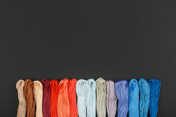 Multicolor threads for embroidery and sewing on black background. Embroidery accessories concept,...