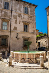Narni, Umbria, Italy - A large fountain in the center of the village of Narni. The old brick town hall building. Blue sky in the summer.