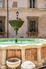 Fototapeta na wymiar Narni, Umbria, Italy - A large fountain in the center of the village of Narni. The old brick town hall building. Blue sky in the summer.