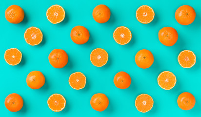 Fruit pattern of fresh mandarin slices over blue background. Flat lay, top view. Pop art design, creative summer concept. Half of citrus in minimal style. Tangerine..