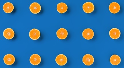 Fruit pattern of fresh orange tangerine or mandarin over blue background. Flat lay, top view. Pop art design, creative summer concept. Citrus in minimal style..