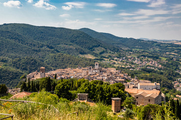 Fototapeta na wymiar View from above of the ancient medieval village of Narni. Umbria, Terni, Italy. The view of the mountains, the trees, the nature. The red roofs of the houses, the bell towers of the churches.