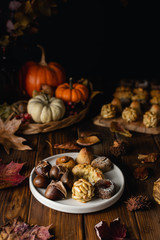 All Saints Day marzipan sweet panellets and roasted chestnuts, autumn leaves on wooden table