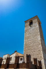 Fototapeta premium A medieval tower in the ancient village of Narni, with old stone and brick buildings. Umbria, Terni, Italy. The blue sky on a summer day.