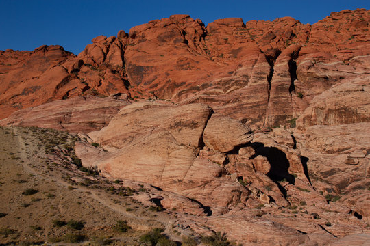 Hikers on a trail at the base of Aztec Sandstone cliffs of Red Rock Canyon in Nevada