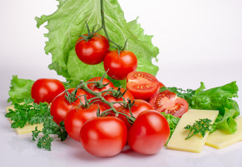ripe tomatoes with lettuce leaves on a white background
