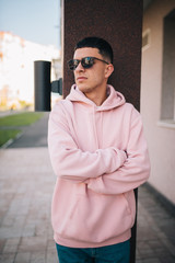 City portrait of handsome hipster guy wearing pink blank hoodie or hoody with space for your logo or design. Mockup for print