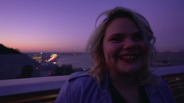 Flirty plump girl smiling at camera, having fun at night roof party, first date