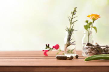 Natural herbal medicine capsules on table with vials and plants