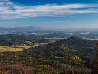 Fototapeta na wymiar Luzicke hory view from Hochwald Hvozd one of the most attractive view-points of the Lusatian Mountains with autumn colored deciduous and coniferous tree forest and green hills, golden hour light
