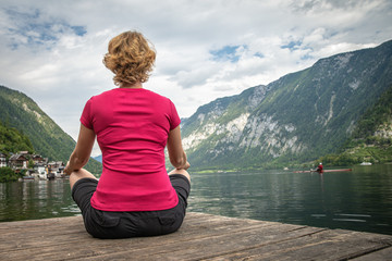 Fototapeta na wymiar A young woman relaxes with a view of a mountain lake after a busy hike
