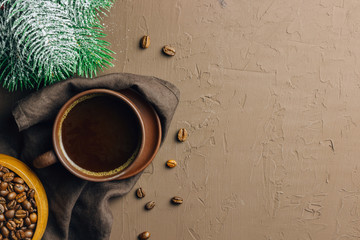 Brown Coffee cup with coffee beans and brown napkin on brown textured background. Top view. Copy space. Flat lay