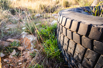 Old wheels of unrecycled cars thrown in a natural field pollute the earth.