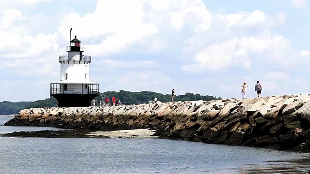 Tourists walking and jogging on the jetty rocks of Spring Point Ledge Lighthouse in South Portland Maine.