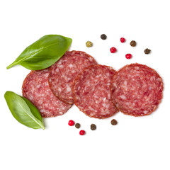 Slices of salami isolated on white background closeup. Sausage and basil leaves top view.
