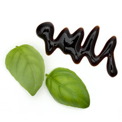 Balsamic vinegar cream and basil leaves isolated on white background. Italian salad dressing, sauce.