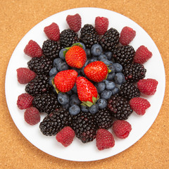 Blackberry, raspberry blueberry and strawberry on a white plate. Vitamins and wholesome foods