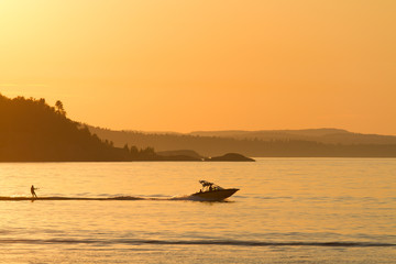 Silhouette of a boat and water skiier at sunset