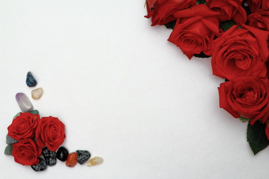 Red roses with smooth pebbles on a white background.