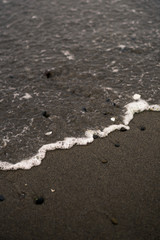 Ocean Shore with a wave washing up the sand and onto rocks