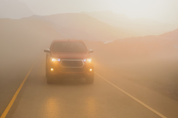 Driving cars in the fog mountain with headlight beams in dense mist.