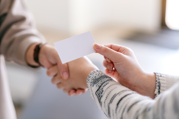 Two people shaking hands and exchanging empty business card