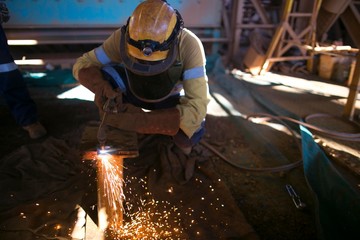 Construction miner worker wearing long sleeve t shirt, safety steel cap boot, hard hat, dark face shield safety protection commencing a oxygen cutting steel plate at mining site Perth Australia  
