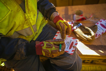 Male industrial construction worker rigger writhing details information on red and white danger...
