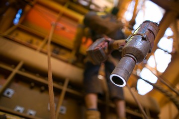 Picture of battery rattle gun clipping connecting into harness lop with blurry  rope access worker working at height at the background construction site, Perth, Australia      