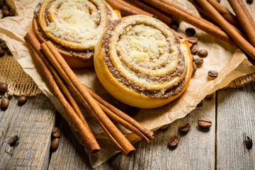Fresh cinnamon buns on the rustic wooden background. Selective focus. Shallow depth of field.