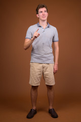 Fototapeta premium Young handsome man wearing gray shirt against brown background