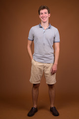 Young handsome man wearing gray shirt against brown background