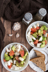 healthy salad from fresh vegetables with avocado, tomatoes and fresh mozzarella cheese served in white bowl