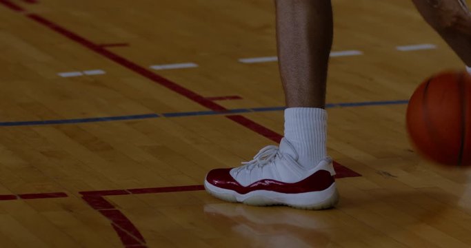 CU on legs, African American black college male basketball player practicing dribbling alone on the indoor court. 4K UHD 120 FPS SLOW MOTION RAW Graded footage