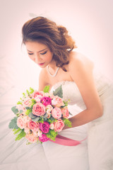 Asian bride sitting with a bouquet of flowers..