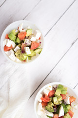 healthy salad from fresh vegetables with avocado, tomatoes and fresh mozzarella cheese served in white bowl