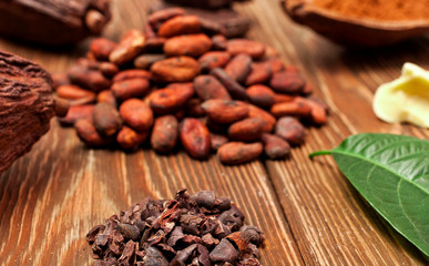 Heaps of cocoa beans and cocoa nibs on wooden background.
