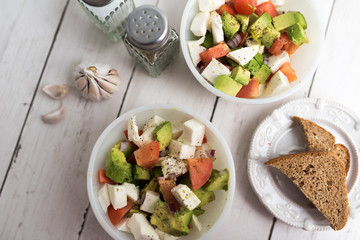 healthy salad from fresh vegetables with avocado, tomatoes and fresh mozzarella cheese served in white bowl