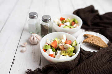 healthy salad from fresh vegetables with avocado, tomatoes and fresh mozzarella cheese served in white bowl