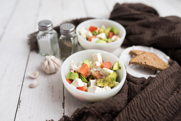 healthy salad from fresh vegetables with avocado, tomatoes and fresh mozzarella cheese served in white bowl