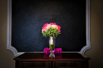 Beautiful flowers in glass vase in the hall. Vintage photo of the interior in classic style.