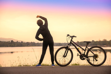 woman standing Exercise stretching on bike with sunrise, sunset after the cycling on road, Sport...