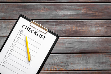 Checklist and pen on dark wooden background top view space for text