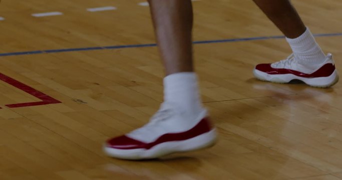 CU on legs, African American black college male basketball player practicing dribbling alone on the indoor court. 4K UHD 120 FPS SLOW MOTION RAW Graded footage