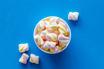 Fluffy dessert. Marshmallows in plate on blue table top view copy space