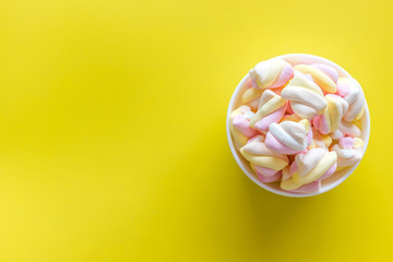 Fluffy dessert. Marshmallows in plate on yellow table top view copy space