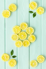 Lemon and leaves pattern on green wooden background top view