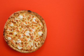 Pizza with salmon and cheese on a red background. Closeup. The concept of delicious food. View from above.